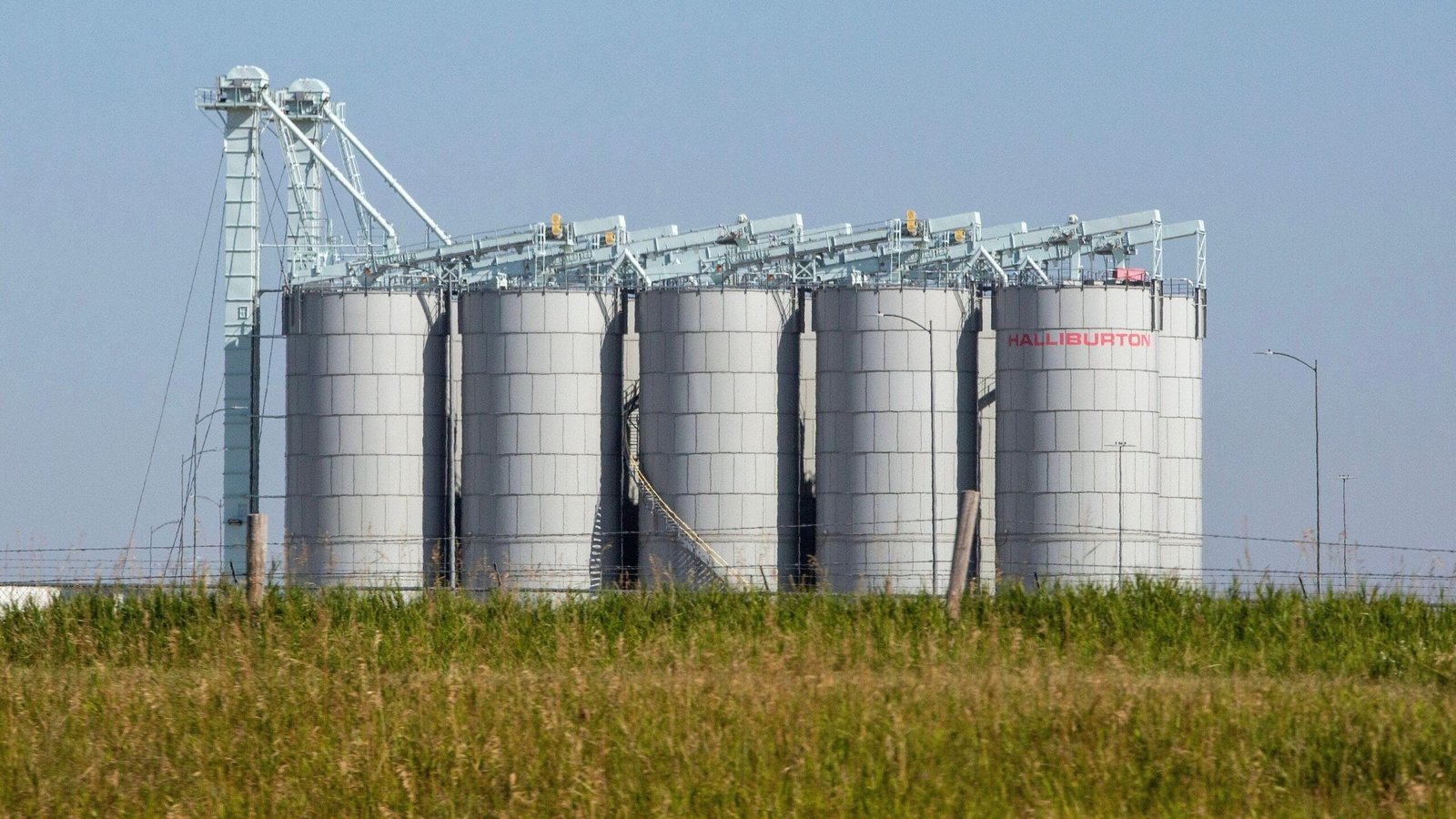 Profissionais de TI analisando um ataque cibernético em ambiente corporativo, com logo da Halliburton ao fundo.