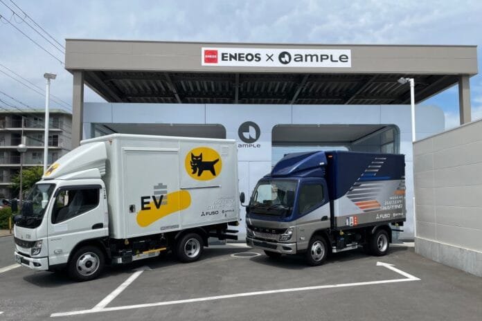 Estação de troca de baterias de veículos elétricos em Madrid com pessoas e carros elétricos ao redor.